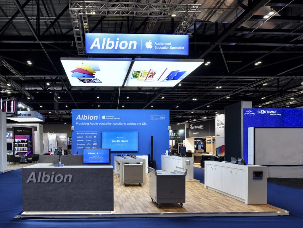 Albion exhibition stand showcasing Apple education solutions, blue branded walls, demo screens, and product display counters